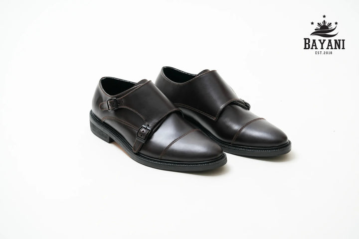 Pair of black leather shoes on a white background with Bayani logo.
