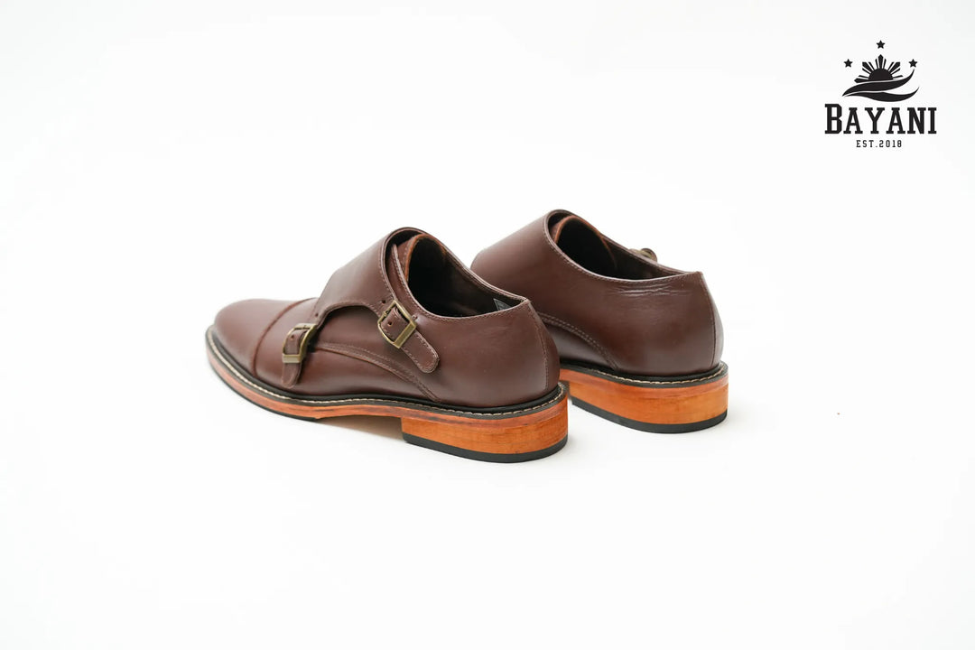 Brown leather shoes with orange soles on a white background, featuring the Bayani logo.
