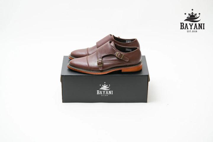 Brown dress shoes on a black Bayani box with the brand logo.
