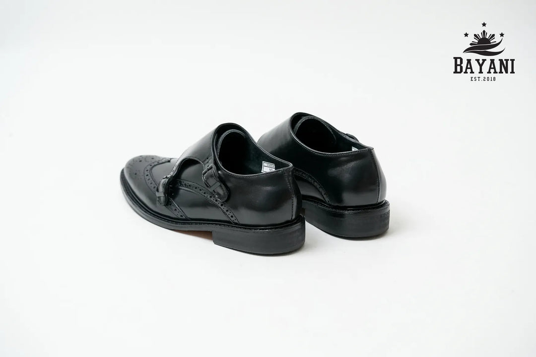 Pair of black leather shoes on a white background with Bayani logo.
