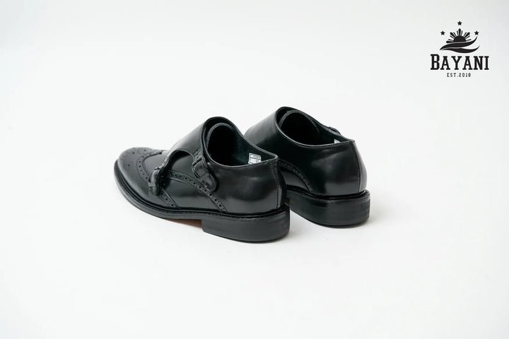 Pair of black leather shoes on a white background with Bayani logo.
