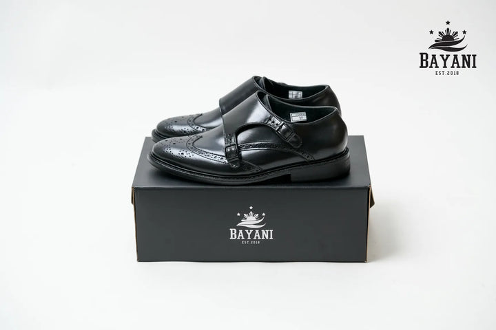 Black dress shoes on a Bayani branded box with the Bayani logo above.
