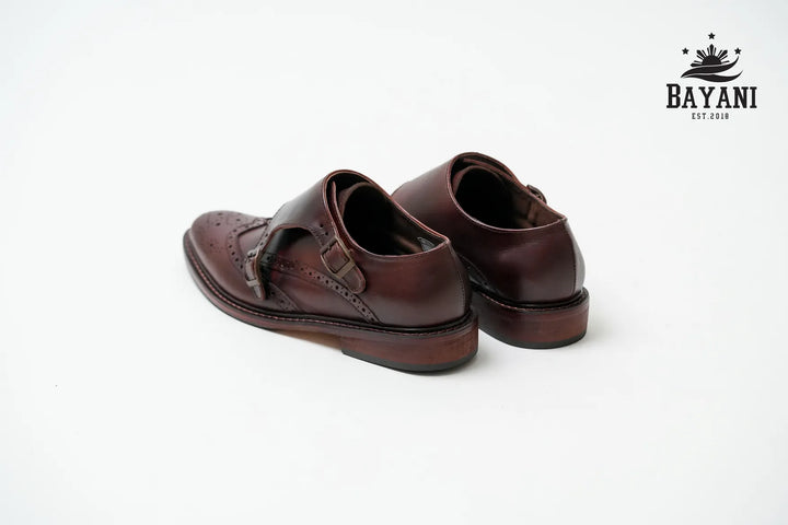 Pair of brown leather shoes on a white background with Bayani logo.
