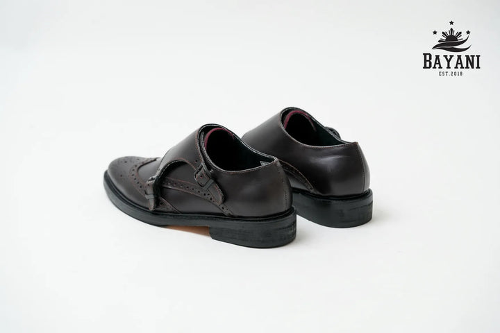 Pair of black shoes with a strap on a white background, featuring the Bayani brand logo.
