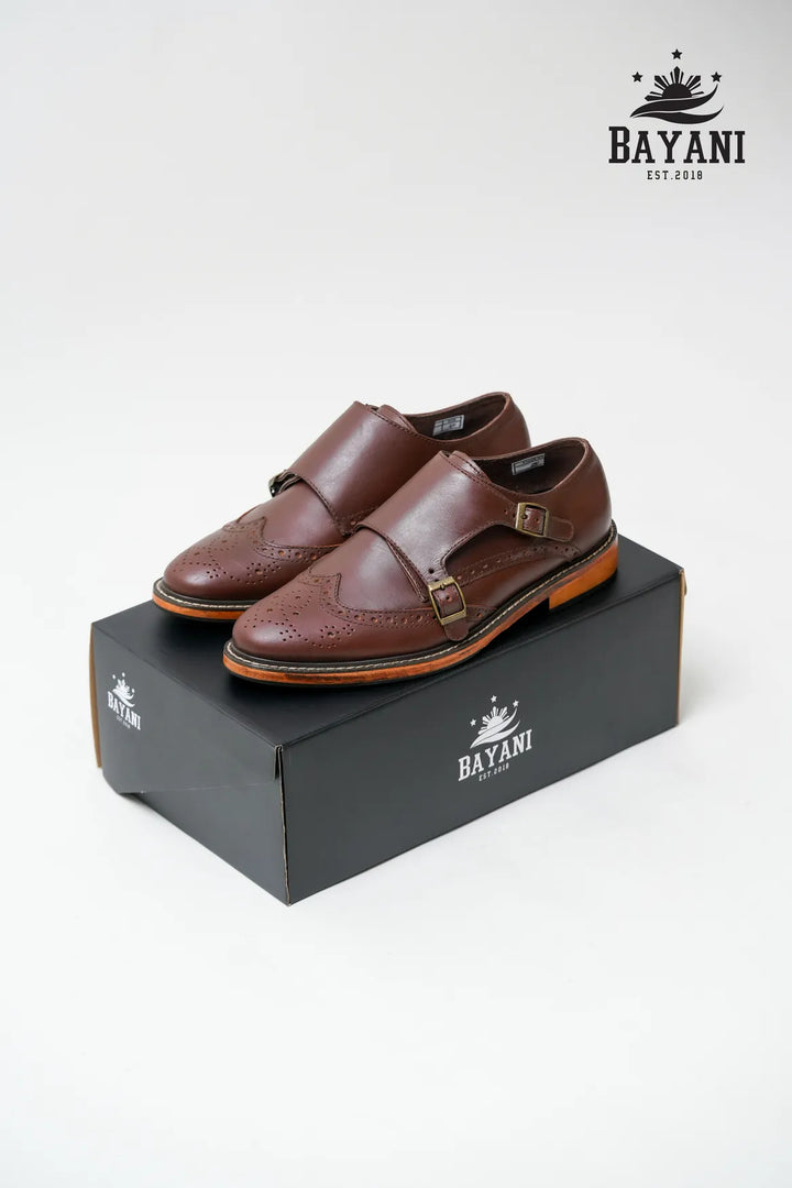 Brown leather shoes on a black box with Bayani logo above, on a white background

