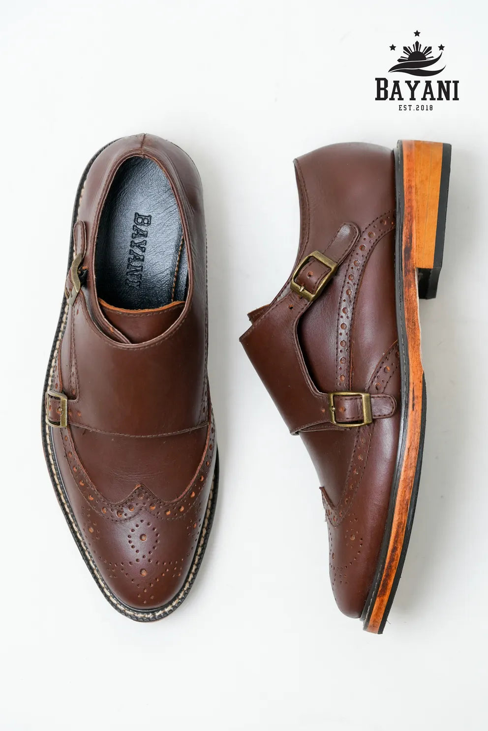 Brown leather shoes with buckles on a white background, featuring the Bayani brand logo.
