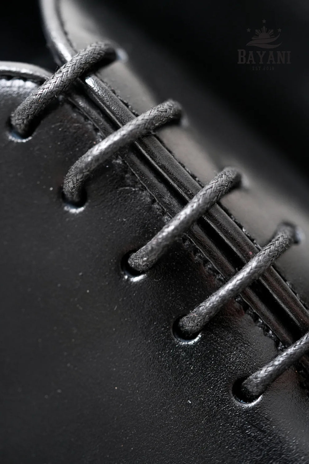 Close-up of black leather shoe laces with 'BAYANI' branding.
#color_black
