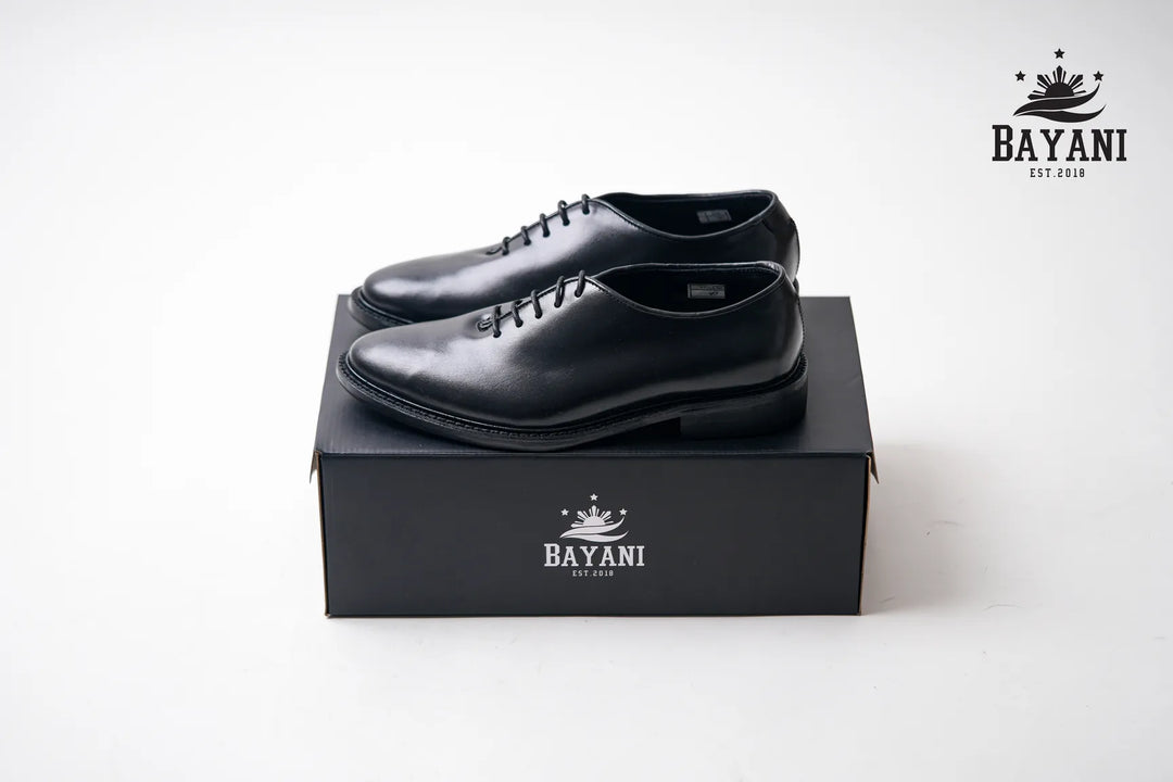 Black dress shoes on a black box with Bayani logo on a white background
