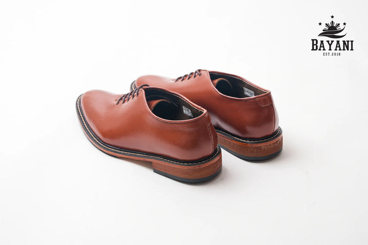 Brown leather shoes on a white background with Bayani logo.
