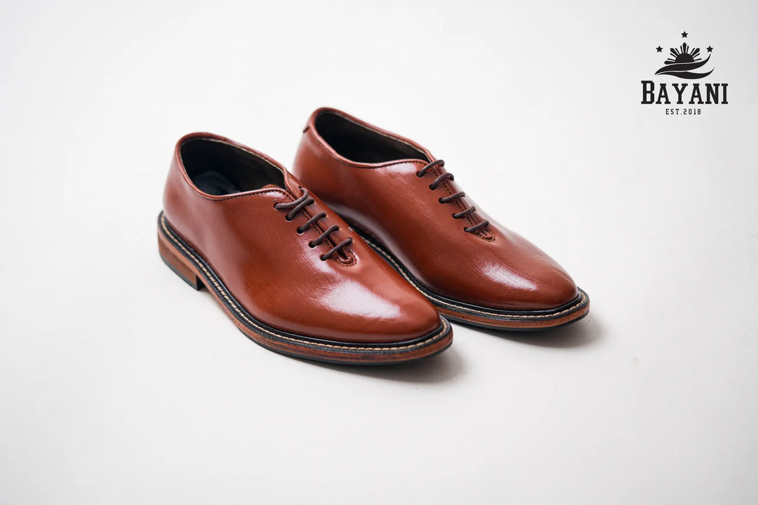 Pair of brown leather shoes on a light gray background with Bayani logo.
