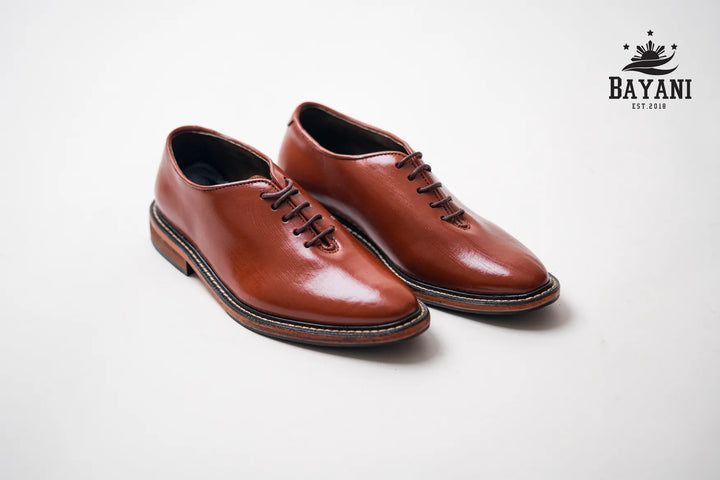 Pair of brown leather shoes on a light gray background with Bayani logo.
