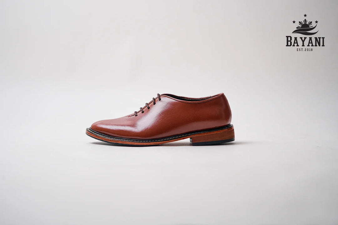 Brown leather shoe on a light gray background with Bayani logo.
