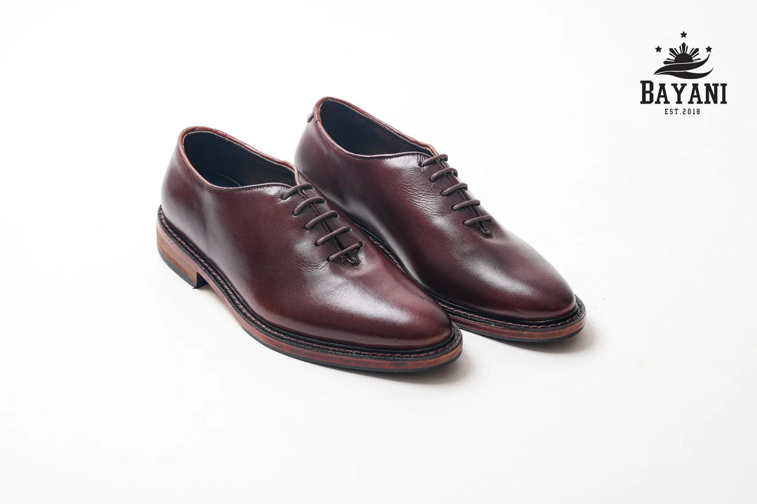 Pair of brown leather shoes on a white background with Bayani logo.

