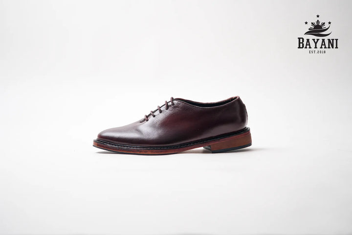 Brown leather shoe on a white background with Bayani logo.

