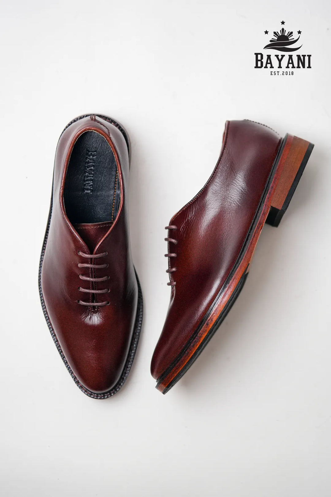 Brown leather dress shoes on a white background with Bayani logo.
