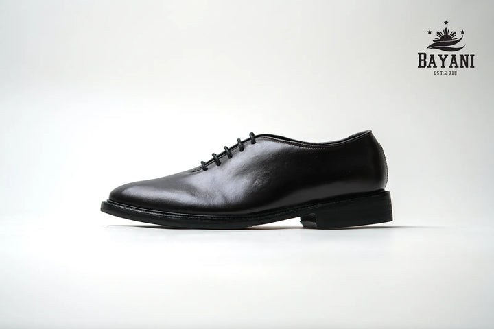 Black leather dress shoe on a white background with Bayani logo.
