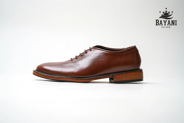 Brown leather shoe on a white background with Bayani logo.

