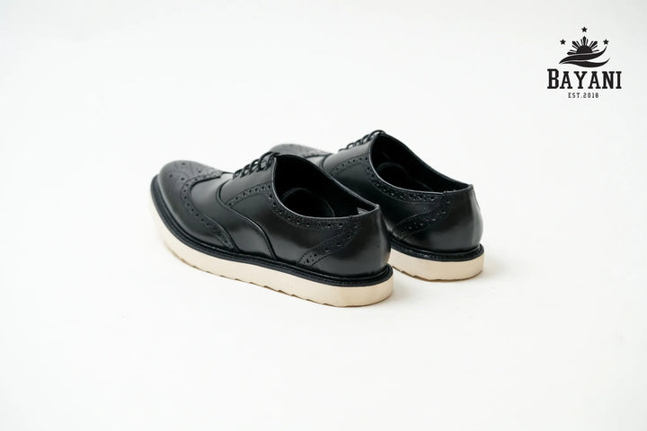 Black leather shoes on a white background with Bayani logo.
