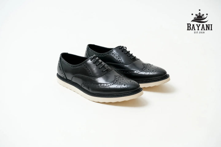 Black leather shoes with white soles on a light gray background, featuring the Bayani logo.
