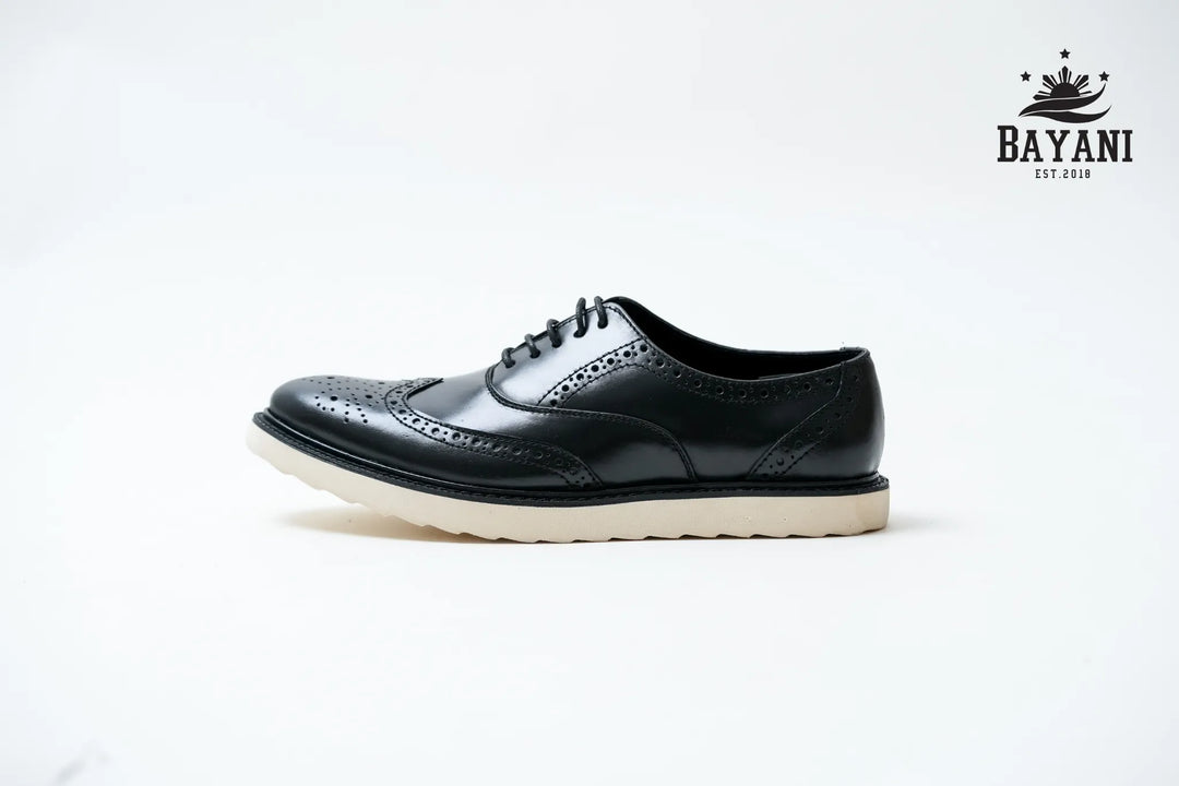 Black leather shoe with white sole on a light gray background, featuring Bayani logo.
