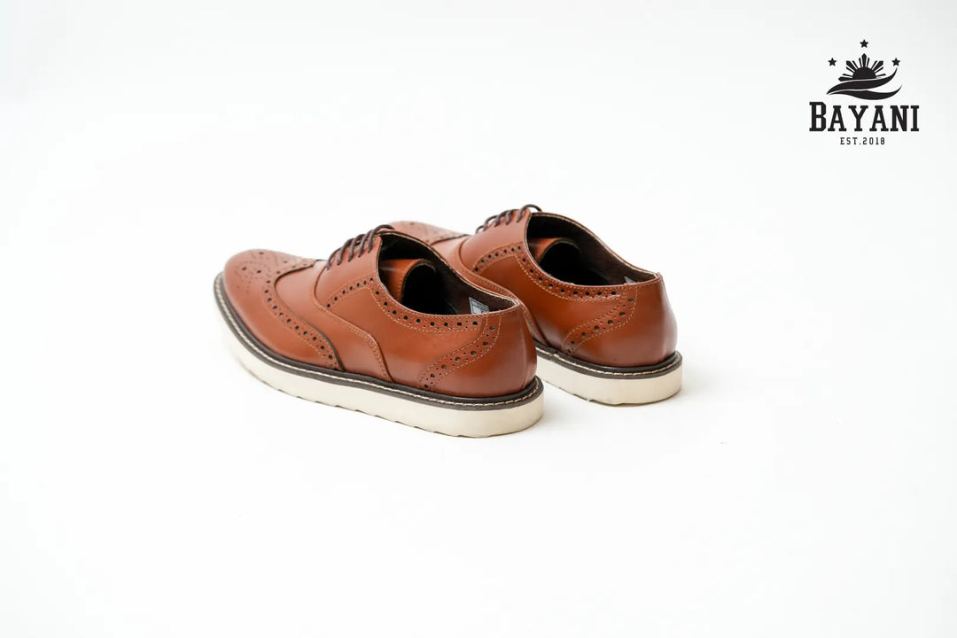 Pair of brown leather shoes on a white background with Bayani logo.

