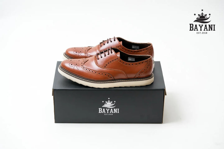 Brown leather shoes on a black box with Bayani logo on a white background
