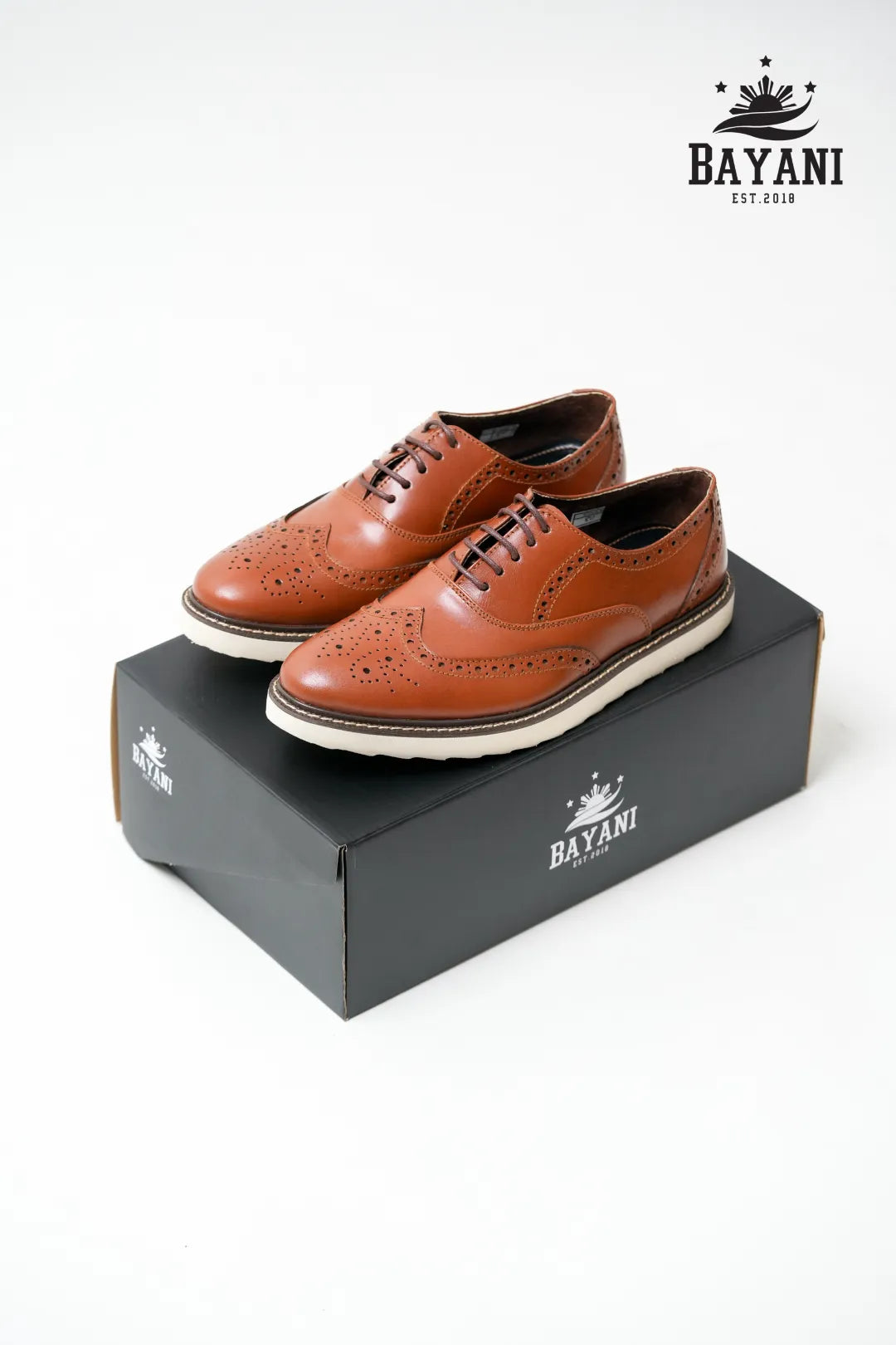 Brown leather shoes on a black Bayani box with the Bayani logo.
