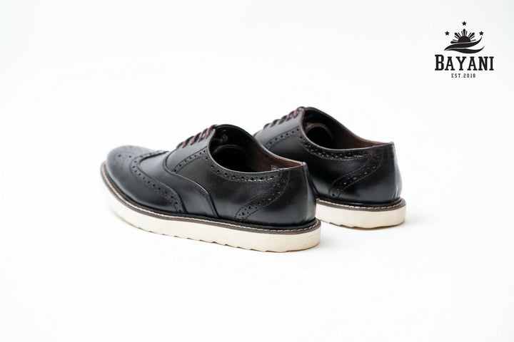 Black leather shoes with white soles on a white background, featuring the Bayani brand logo.
