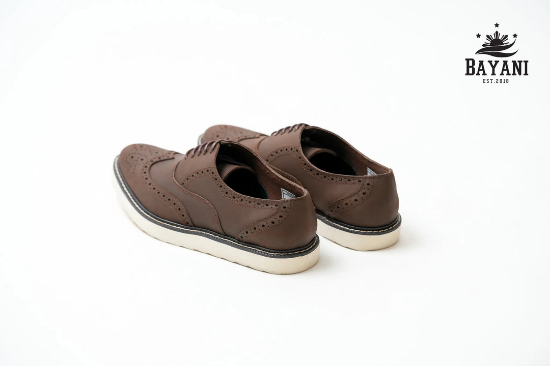 Brown leather shoes with white soles on a white background, featuring the Bayani brand logo.
