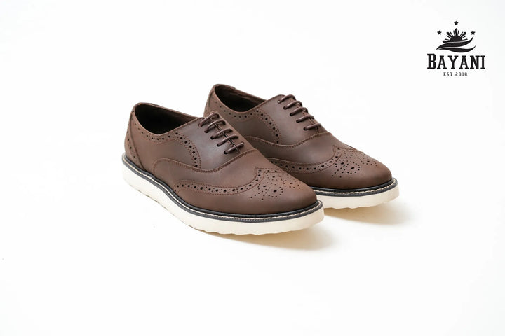 Pair of brown leather shoes with white soles on a white background, featuring the Bayani brand logo.
