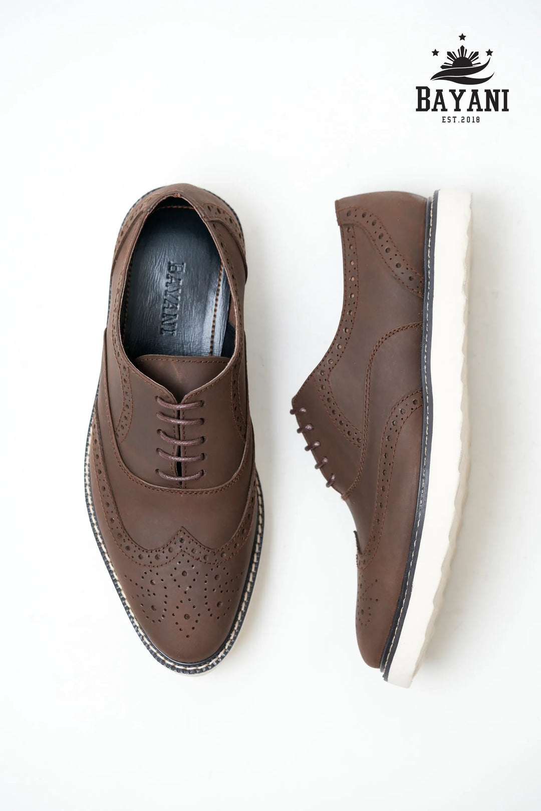 Brown dress shoes with white soles on a white background, featuring the Bayani brand.
