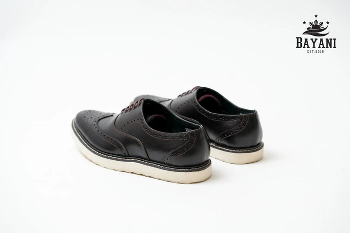 Black leather shoes on a white background with Bayani logo.
