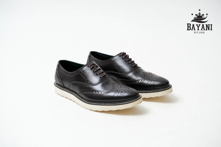 Black leather shoes with white soles on a light gray background, featuring the Bayani brand logo.
