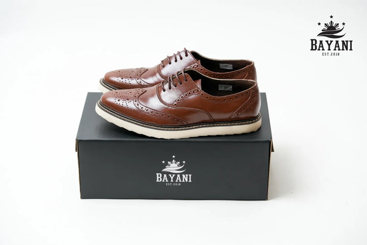 Brown leather shoes on a black Bayani box with the brand logo.

