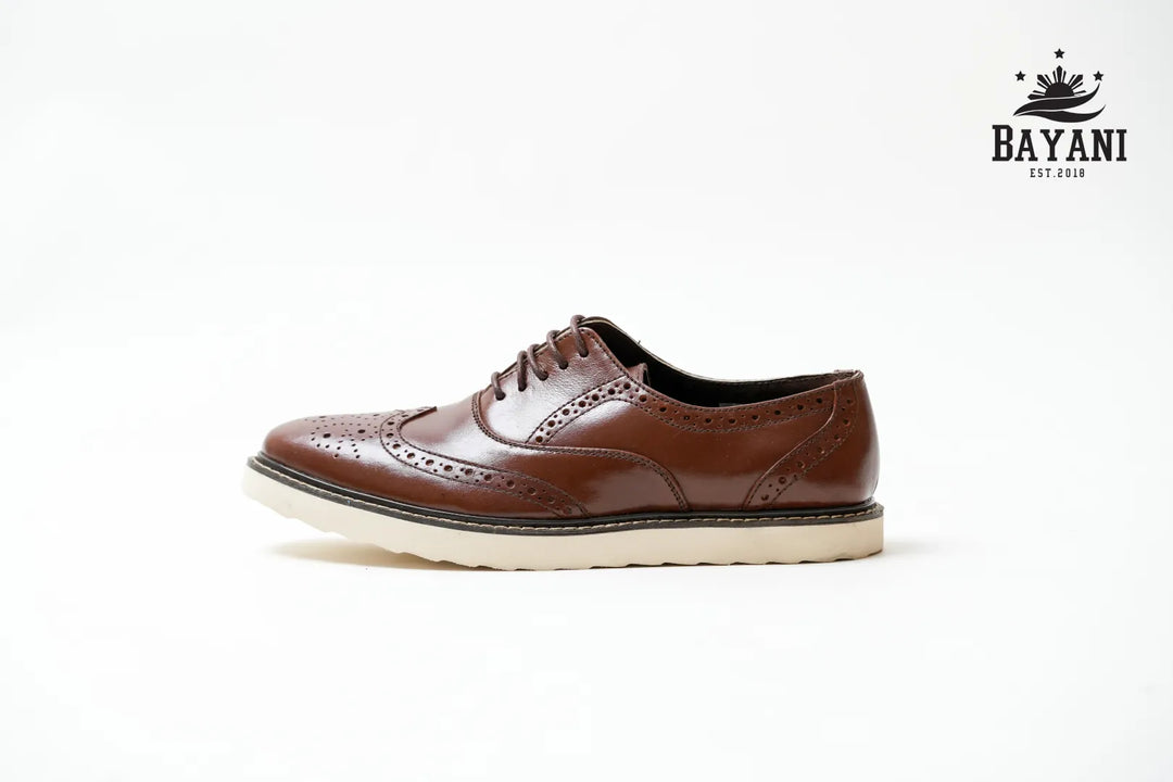 Brown leather shoe with white sole on a light gray background, featuring the Bayani brand logo.
