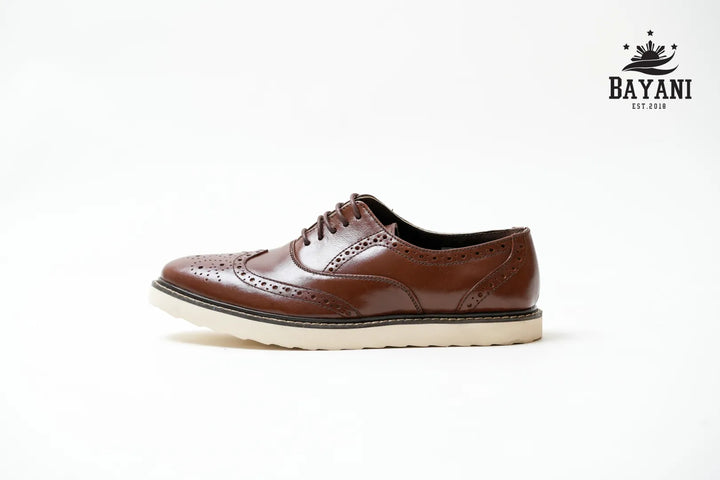 Brown leather shoe with white sole on a light gray background, featuring the Bayani brand logo.
