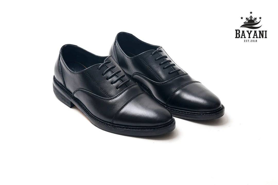 Pair of black dress shoes on a white background with Bayani logo.
#color_black
