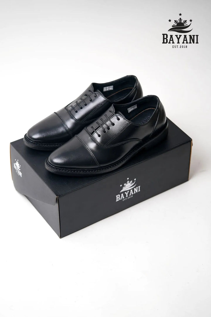 Black dress shoes on a black Bayani box with the brand logo.
