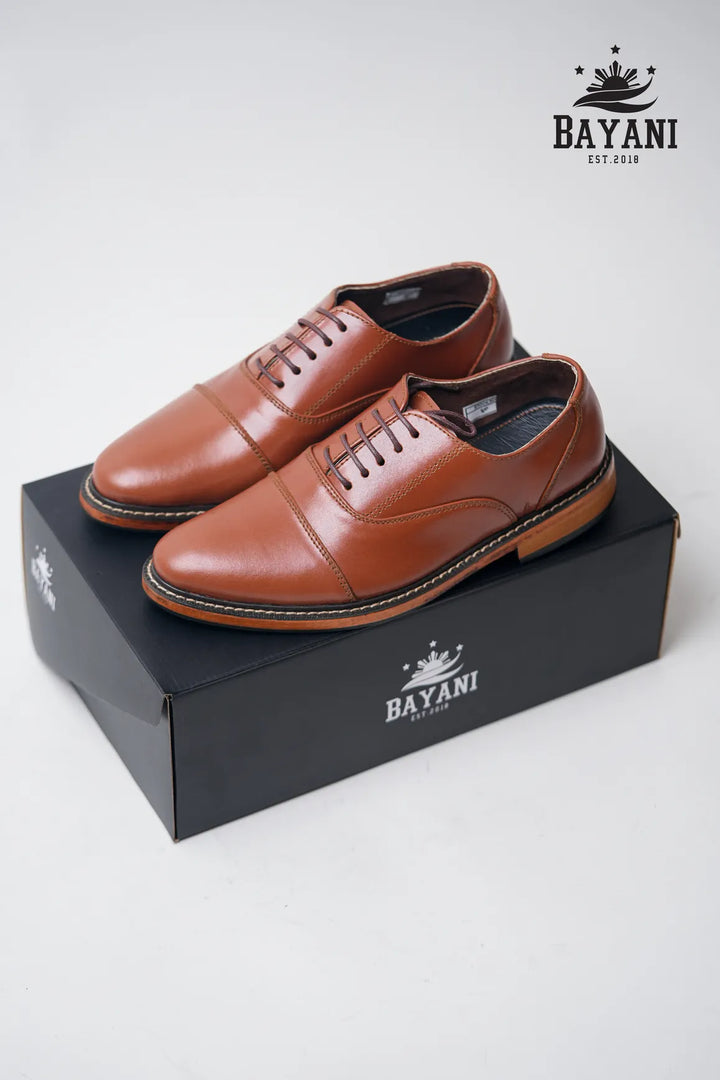 Brown leather shoes on a black Bayani box with the brand logo.
