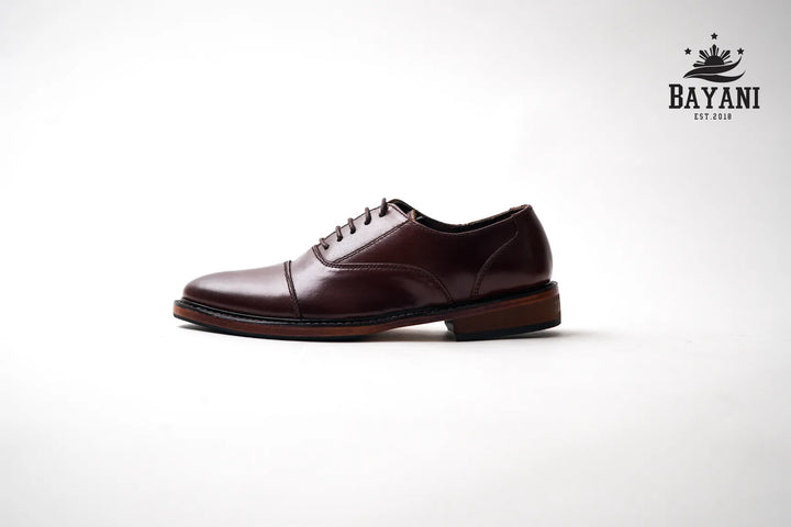 Brown dress shoe on a white background with Bayani logo.
