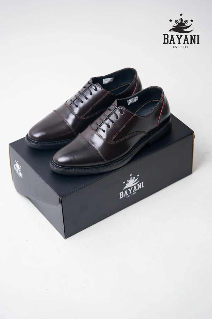 Brown dress shoes on a black Bayani box with the brand logo.
