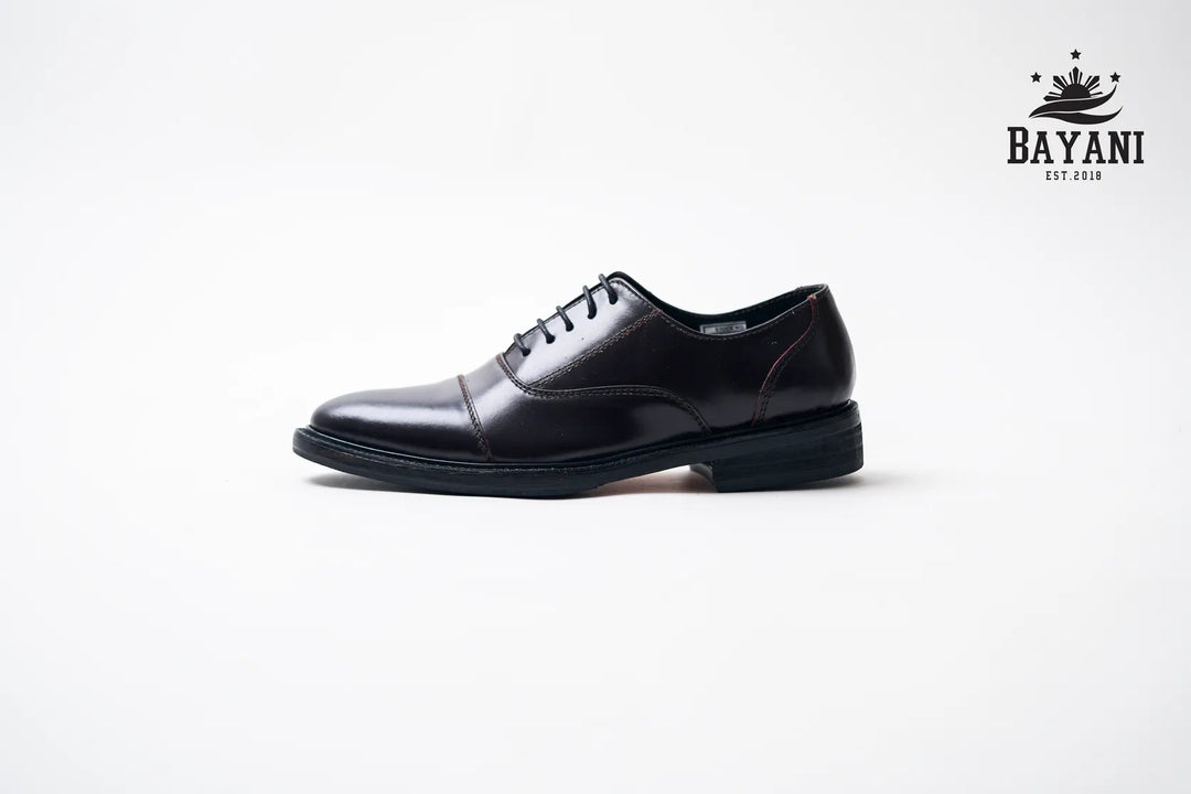 Black dress shoe on a white background with Bayani logo.
