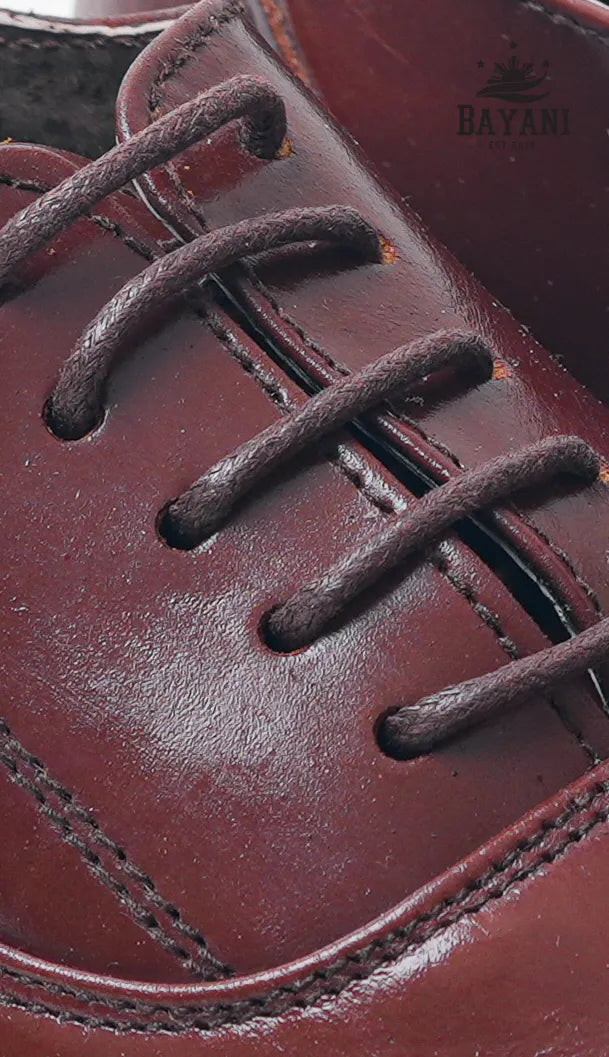 Close-up of a brown leather shoe with laces, featuring the Bayani brand.
