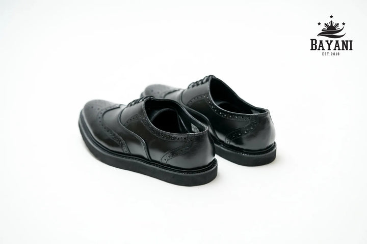 Pair of black dress shoes on a white background with Bayani logo.
