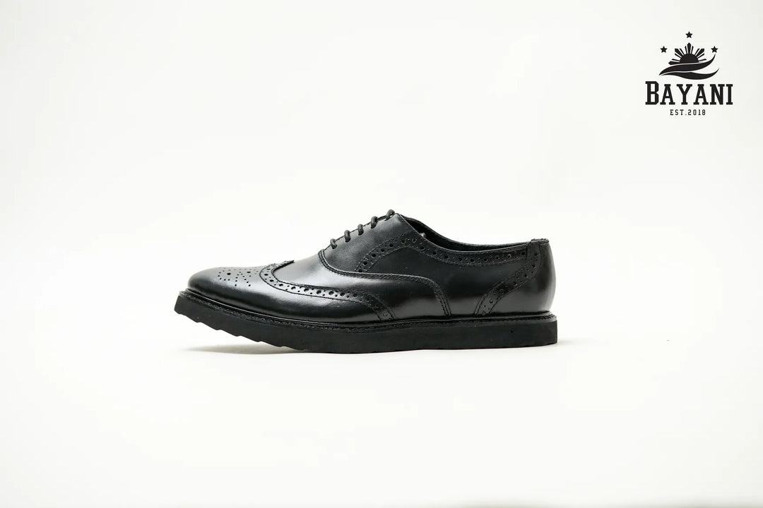 Black leather shoe on a white background with Bayani logo.
