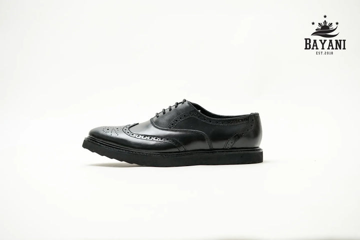 Black leather shoe on a white background with Bayani logo.
