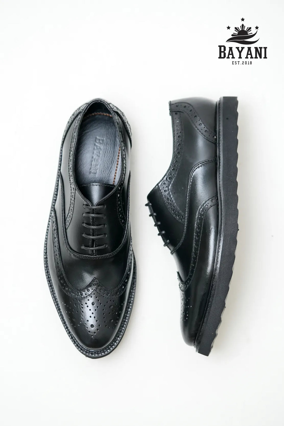 Black leather shoes on a white background with Bayani logo.
