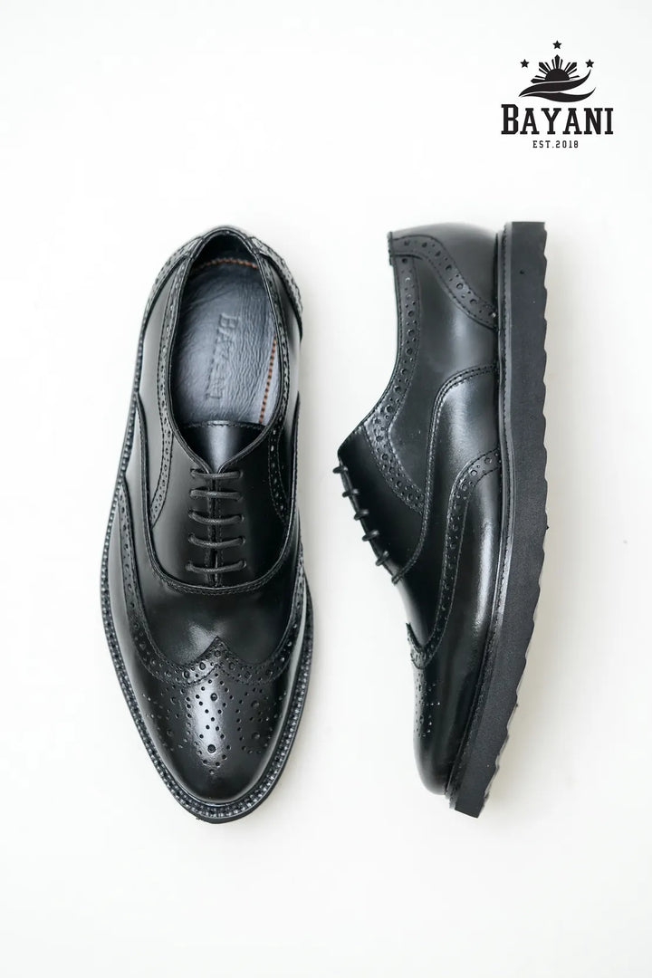 Black leather shoes on a white background with Bayani logo.
