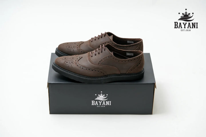 Brown leather shoes on a black box with Bayani logo on a white background
