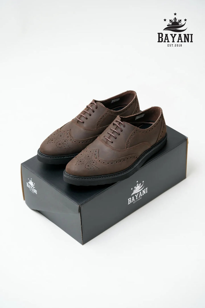 Brown leather shoes on a Bayani branded box with the Bayani logo above.
